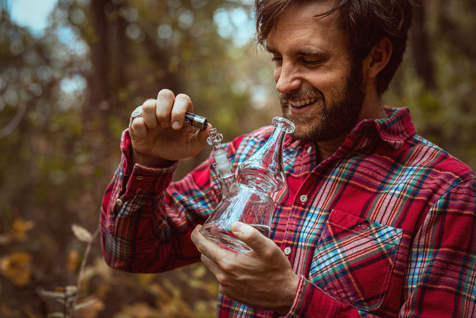 smiling man using clear glass bong